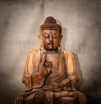 wooden buddha on grey background