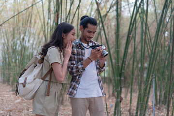 Male and female tourists are touring nature and taking pictures of the scenery. Couples go wild together on weekends. Nature tourism concept.