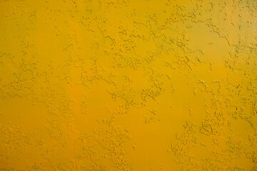 Abstract background of dark yellow color with splashes of green paint. Decorative plaster or wall painted with yellow paint over an old layer of green paint. Old rusty metal painted yellow
