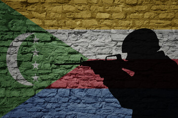 Soldier silhouette on the old brick wall with flag of comoros country.