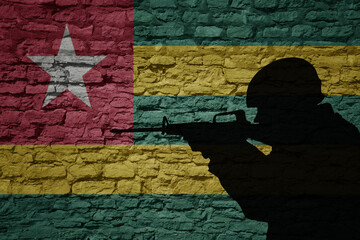 Soldier silhouette on the old brick wall with flag of togo country.