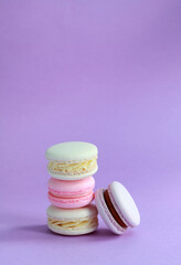 Macaron or macaroon on lilac background, colorful almond cookies with different fillings
