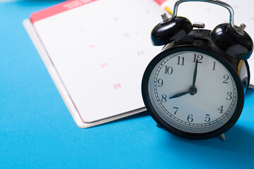 close up of calendar and alarm clock on the blue table background, planning for business meeting or travel planning concept
