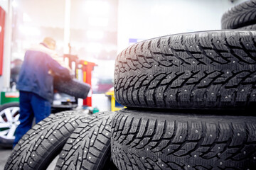 Auto mechanic in uniform is winter tires replacement working in service