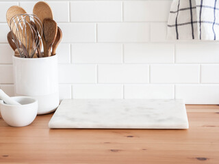 Stylish white kitchen background with kitchen utensils standing on wood countertop near white wall...