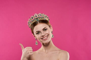 attractive woman with a crown on her head makeup decoration pink background