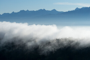 Layers of clouds and forest with mountains in the background