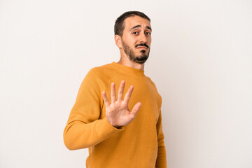 Young caucasian man isolated on white background being shocked due to an imminent danger