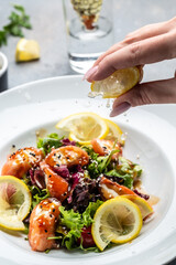 salmon salad with lettuce greens and lemon. splashes of lemon juice, Food recipe background. Close up