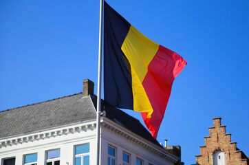 Brugge, Belgium - October 9. 2021: View on isolated belgian flag with blurred stepped gabled house...