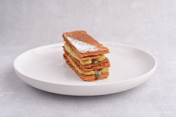 Mille-feuille dessert with caramel, vanilla and pumpkin cream on the plate