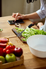 Woman is cooking  in the kitchen at home, using digital tablet or smarthone, looking recipe, Healthy food concept, vegan or diet..