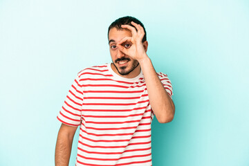 Young caucasian man isolated on blue background excited keeping ok gesture on eye.