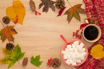Naklejka na ściany i meble Autumn composition with a cup of coffee, marshmallows and leaves. Shot from above on a wooden background.