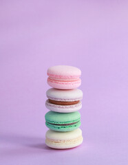 Macaron or macaroon on lilac background, colorful almond cookies with different fillings