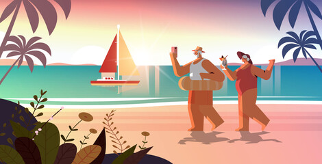 Obraz premium senior couple drinking cocktail and using smartphone on tropical beach grandparents having fun summer vacation