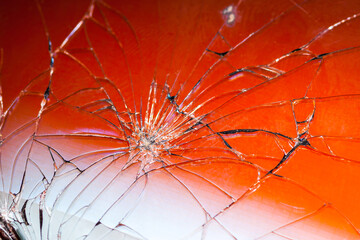 Close-up of a broken smartphone glass, red background