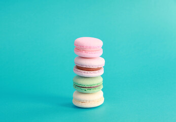 Macaron or macaroon on turquoise background, colorful almond cookies with different fillings