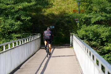 Cyclist passing bridge over Rhine river near City of Neuhausen am Rheinfall. Photo taken September 25th, 2021, Neuhausen am Rheinfall, Switzerland.