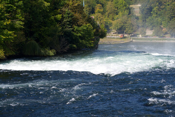 Famous Rhine Falls with rocks and trees on a beautiful autumn day. Photo taken September 25th, 2021, Zürich, Switzerland.