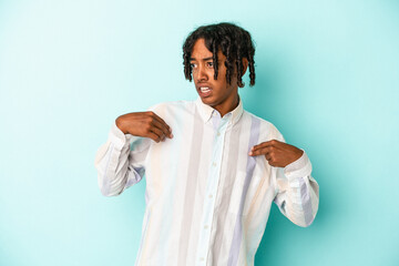 Young african american man isolated on blue background surprised pointing with finger, smiling broadly.