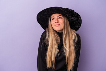 Young Russian woman disguised as a witch celebrating Halloween isolated on purple background dreaming of achieving goals and purposes