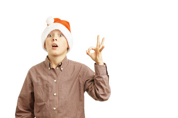 portrait of surprised child in santa hat shows ok with fingers, isolated on white background.