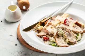 Delicious chicken caesar salad with parmesan cheese, chicken breasts and fresh vegetables
