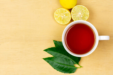Neem tea in ceramic cup with neem leaf and lemon on wooden background, top view.