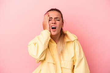 Young Russian woman isolated on pink background tired and very sleepy keeping hand on head.