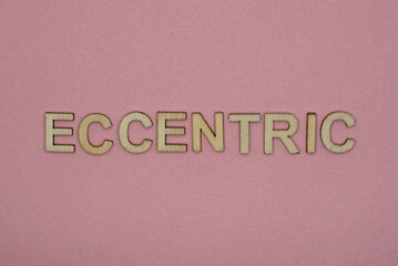 text the word eccentric from gray wooden small letters on an pink table