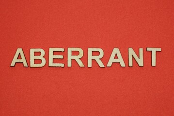 Fototapeta na wymiar text the word aberrant from gray wooden small letters on an red table
