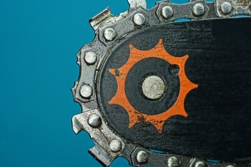 part of a black electric saw with gray sharp iron teeth on a blue background