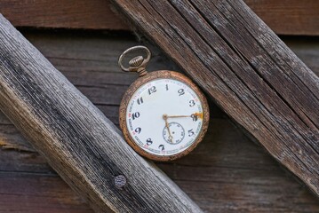 one old rarity pocket watch lies on brown wooden planks table