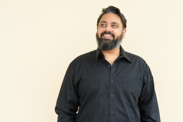 Plus size handsome bearded Indian man against plain background