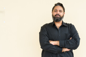 Obraz premium Portrait of handsome bearded Indian man against plain background