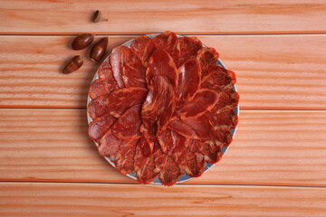 Portion of 100% acorn-fed Iberian loin on wooden table, adorned with acorns