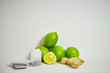 lime, ginger and tea bags on a white background