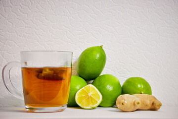 cup with tea , ginger and lime on a white background