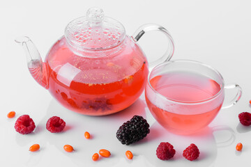 Delicious tea of berries and fruits in a beautiful glass teapot on a white background with reflection