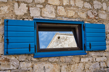 reflections in a lonely blue window in the wall