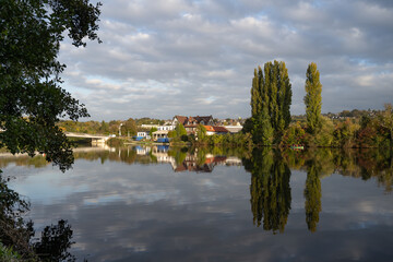 Fototapeta premium Blick über die Ruhr auf Essen Kupferdreh. Typische Herbstlandschaft im Ruhrgebiet. Bäume und Gebäude spiegeln sich im Wasser der Ruhr.