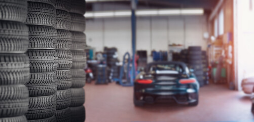 Plakat tire at repairing service garage background. Technician man replacing winter and summer tyre for safety road trip. Transportation and automotive maintenance concept