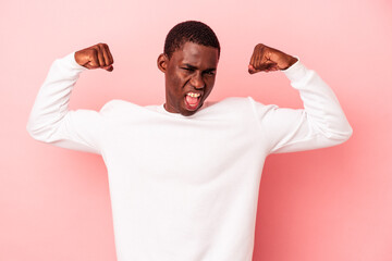 Young African American man isolated on pink background showing strength gesture with arms, symbol of feminine power