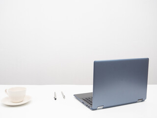 Laptop with coffee cup and pen on the table workplace in the room white background