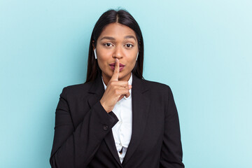 Young Venezuelan business woman isolated on blue background keeping a secret or asking for silence.