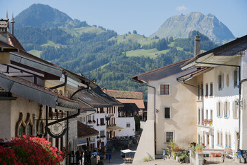 Fototapeta na wymiar Calle principal del pueblo de Gruyeres, Suiza. Vistas a la montaña con las casas y flores