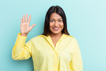 Young Venezuelan woman isolated on blue background smiling cheerful showing number five with fingers.