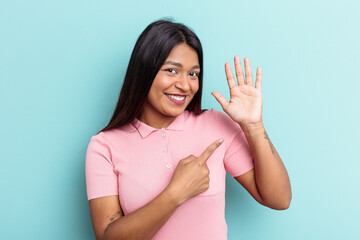 Young Venezuelan woman isolated on blue background smiling cheerful showing number five with...