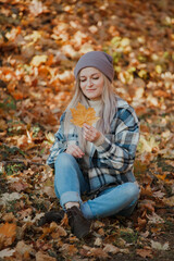 Fototapeta na wymiar a blonde girl in a plaid shirt in the autumn forest
